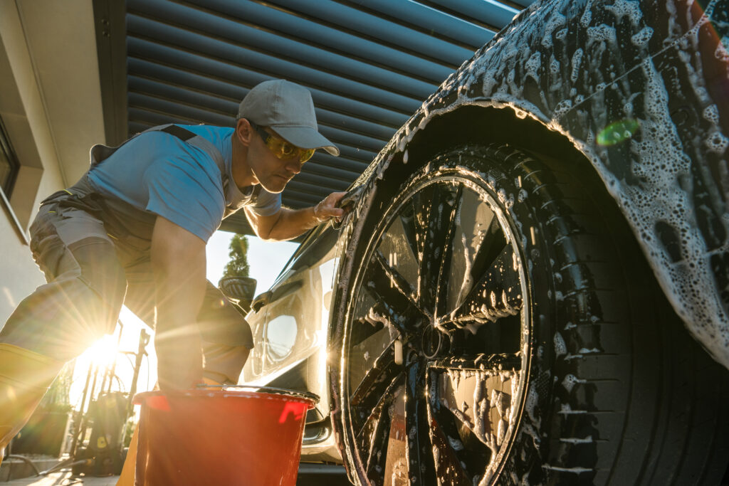 Man washing and detailing a black vehicle during spring car cleaning in Leamington